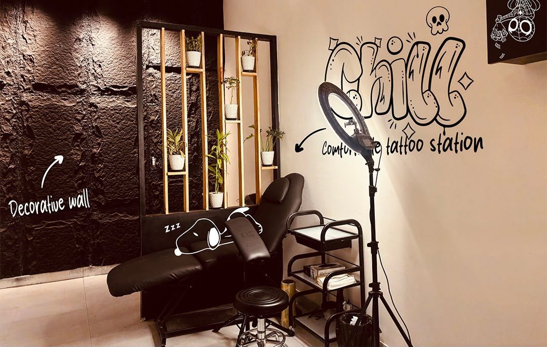 The tattoo chair beside the black textured wall and plant shelf