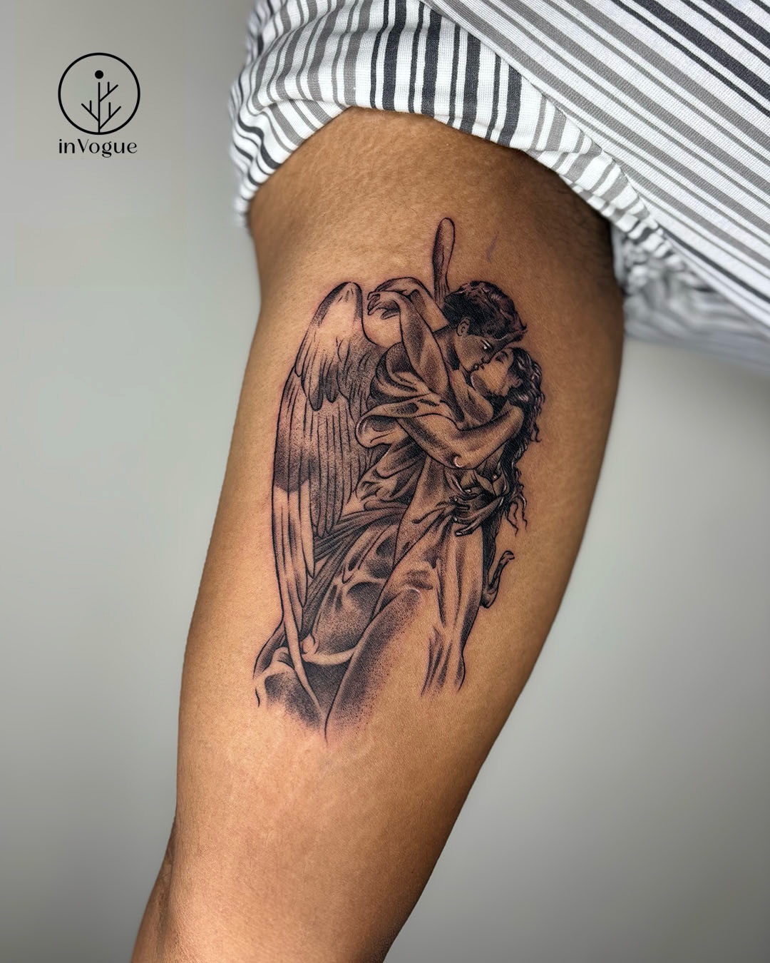 Black and grey realism angel embracing tattoo on thigh