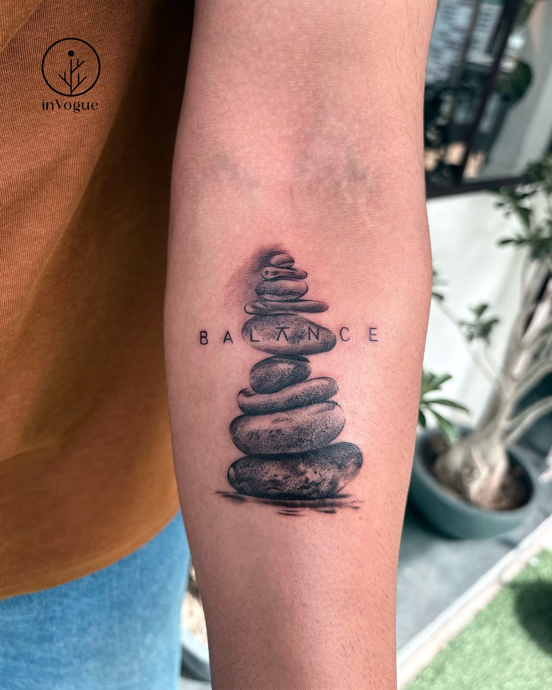 Fine line stacked balancing stones tattoo with the word balance