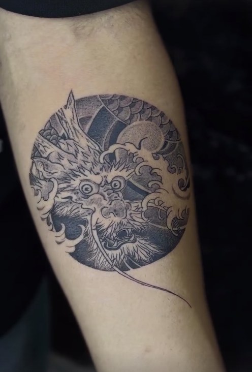 Circular dotwork dragon and waves tattoo on a forearm